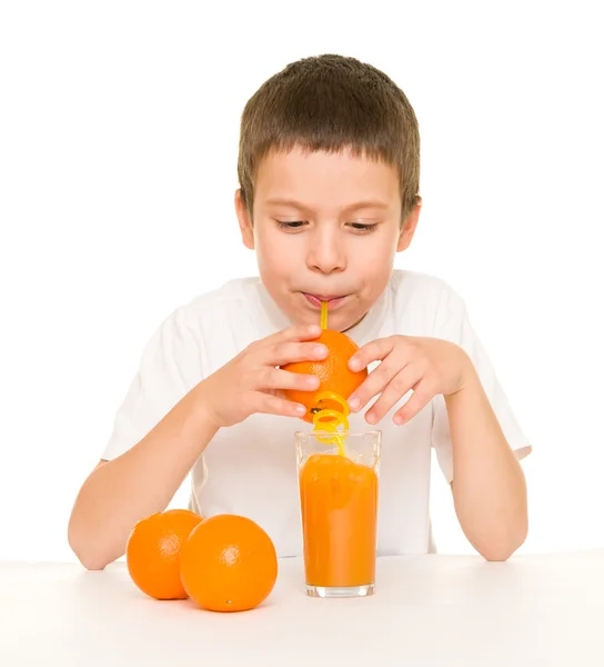 Мальчик пьет апельсиновый сок с соломинкой — стоковое фото