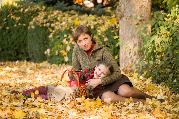 Femme et petite fille dans le parc d'automne avec panier de pomme — Photo