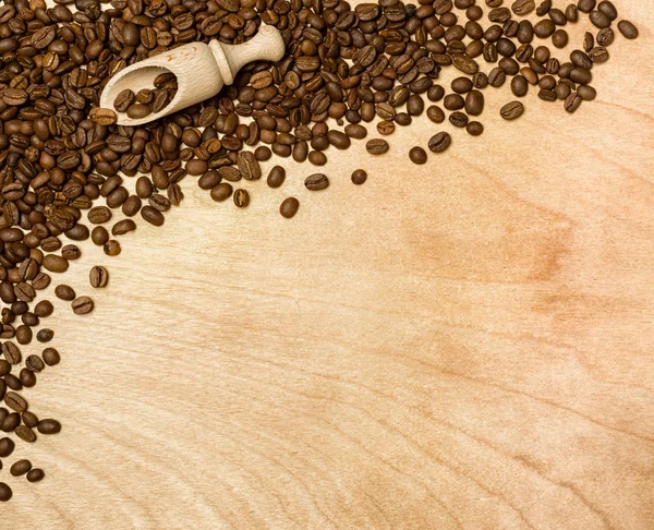 Coffee seeds with wooden shovel on wood background — Stock Photo, Image