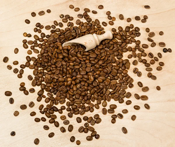Semillas de café con pala de madera sobre fondo de madera —  Fotos de Stock