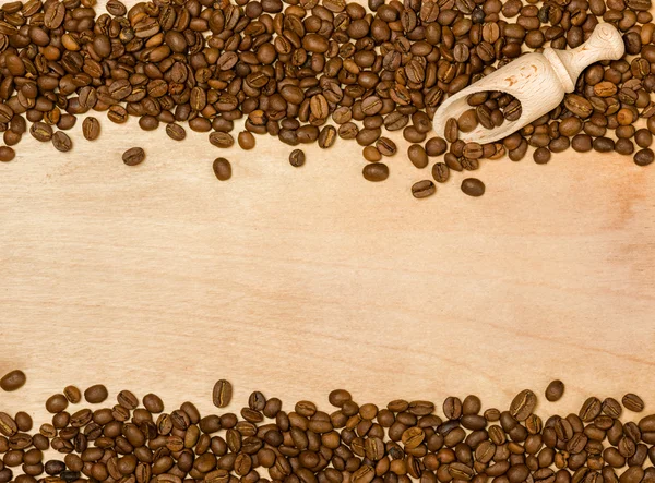 Semillas de café con pala de madera sobre fondo de madera — Foto de Stock