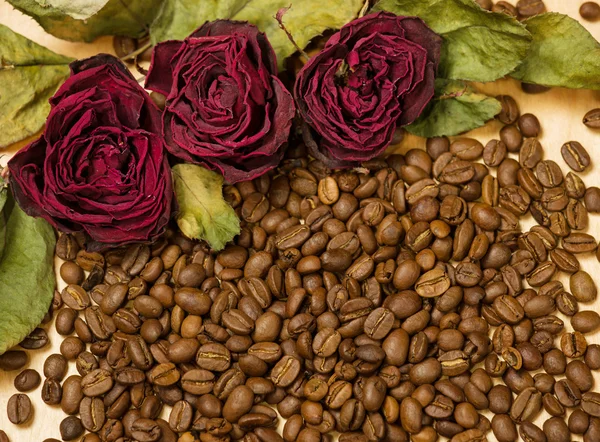 Rose rosse secche su semi di caffè e fondo in legno — Foto Stock
