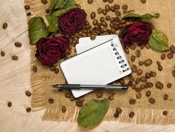 Чистый лист и сухие красные розы на семенах кофе — стоковое фото