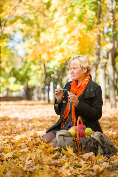 Pregnant woman blow bubbles in autumn park — Stock Photo, Image