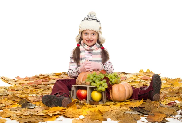 Ragazza con frutta e verdura sulle foglie d'autunno — Foto Stock