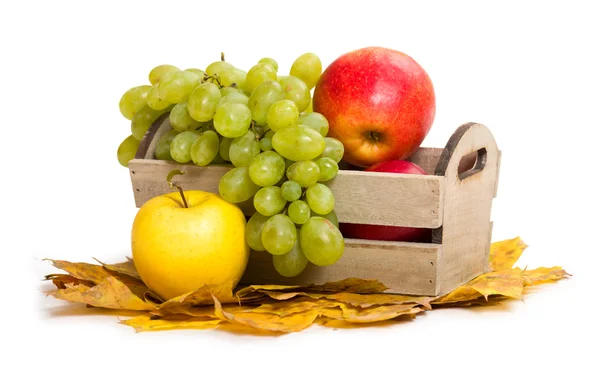 Pommes et raisins en caisse sur les feuilles d'automne — Photo