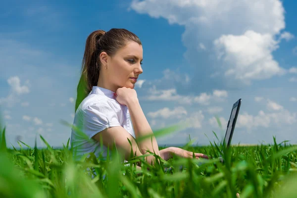 Girl with laptop on green field — Stock Photo, Image