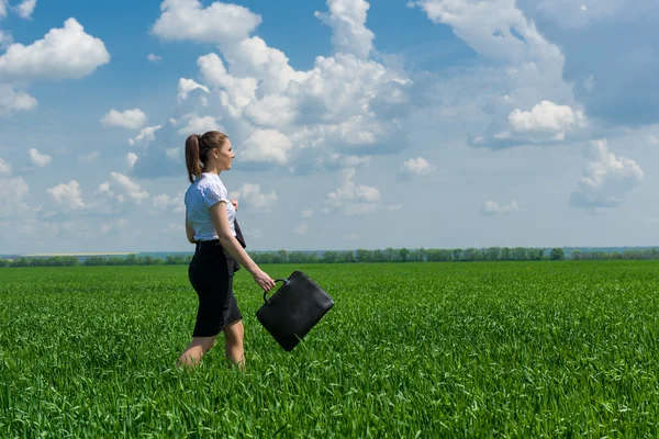 Ragazza con una valigetta che cammina sull'erba — Foto Stock