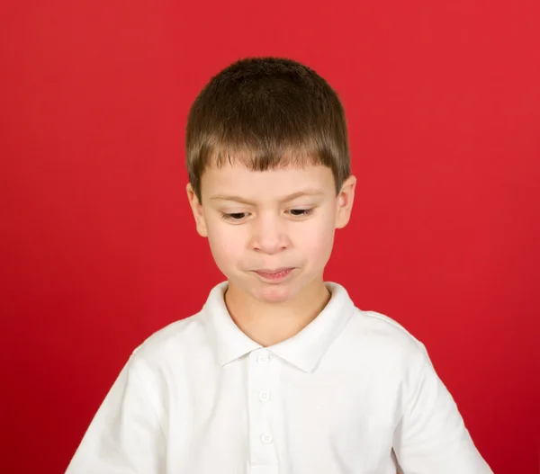 Grimaserande pojke porträtt på rött — Stockfoto