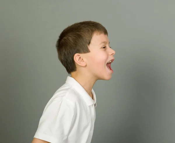 Grimaserande pojke porträtt på grå — Stockfoto