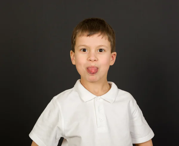 Grimaserande pojke porträtt på svart — Stockfoto