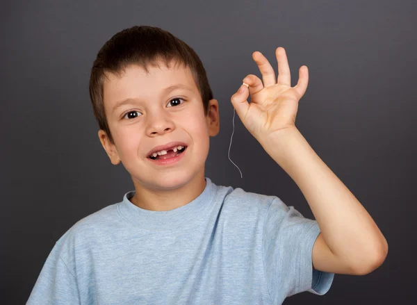 Boy with lost tooth on thread — Stock Photo, Image