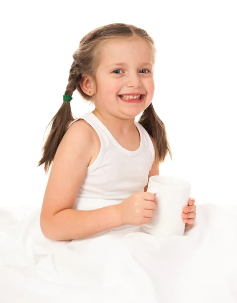 Girl with cup in white bed — Stock Photo, Image