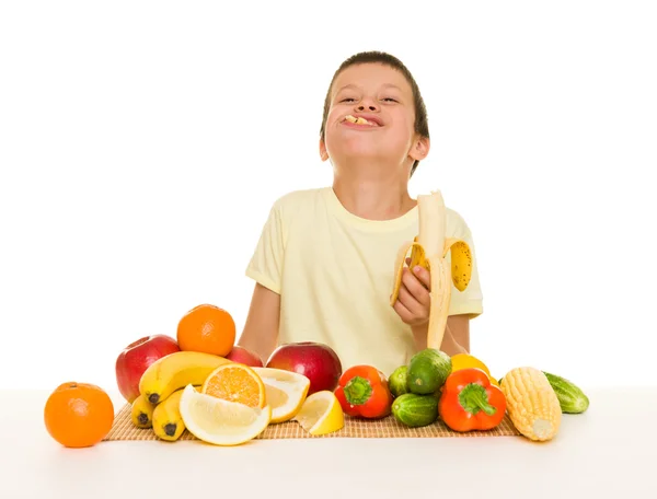 Menino com frutas e legumes comer banana — Fotografia de Stock