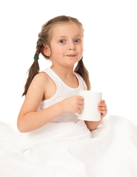 Girl with cup in white bed — Stock Photo, Image