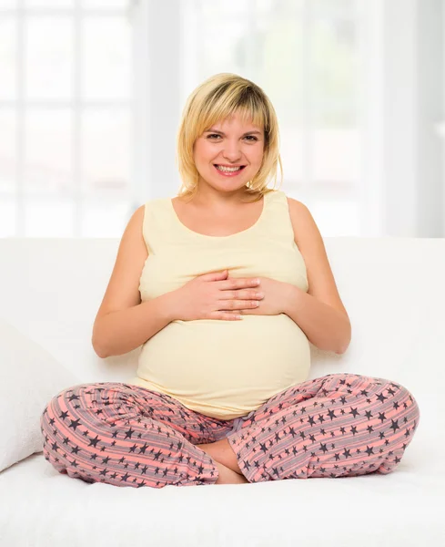 Pregnant woman in bed with red hearts — Stock Photo, Image