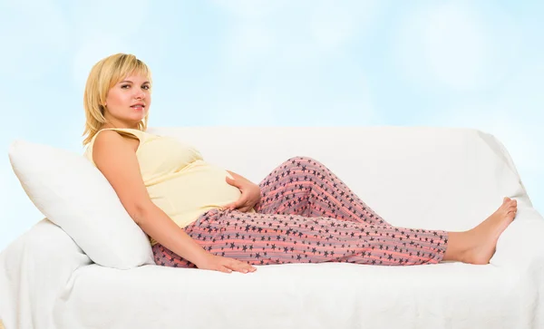 Mulher grávida na cama. Fundo azul bokeh — Fotografia de Stock