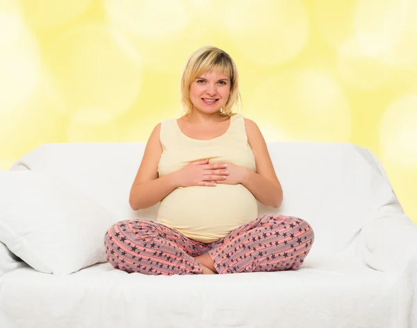 Pregnant woman in bed. Yellow bokeh background — Stock Photo, Image