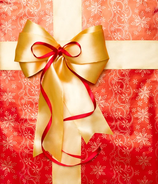 Golden bow with red ribbon on box top — Stock Photo, Image