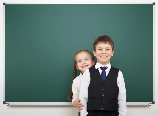 Schooljongen en schoolgirl in de buurt van het schoolbestuur — Stockfoto