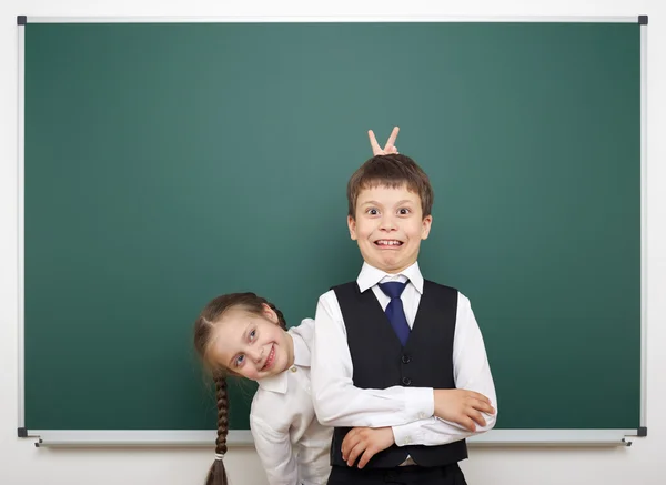 Schoolboy and schoolgirl near the school board — Stock Photo, Image