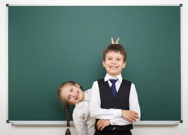 Schoolboy and schoolgirl near the school board — Stock Photo, Image