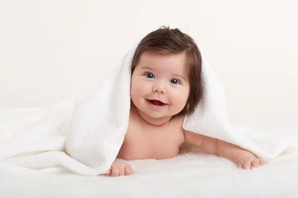 Glückliches Baby unter Handtuch auf weiß — Stockfoto