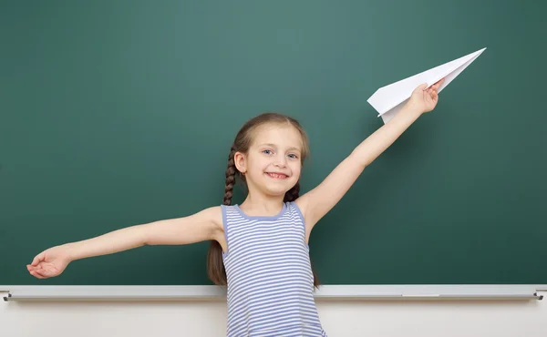 Chica cerca de la junta escolar con avión de papel —  Fotos de Stock