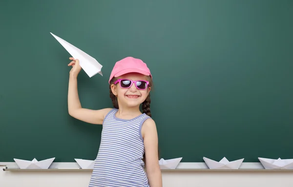 Girl near school board with paper plane and boat — Stock Photo, Image