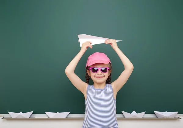 Girl near school board with paper plane and boat — Stock Photo, Image