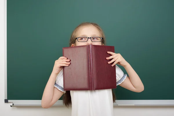 Colegiala con libro cerca de la junta escolar —  Fotos de Stock