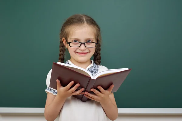 Colegiala con libro cerca de la junta escolar — Foto de Stock