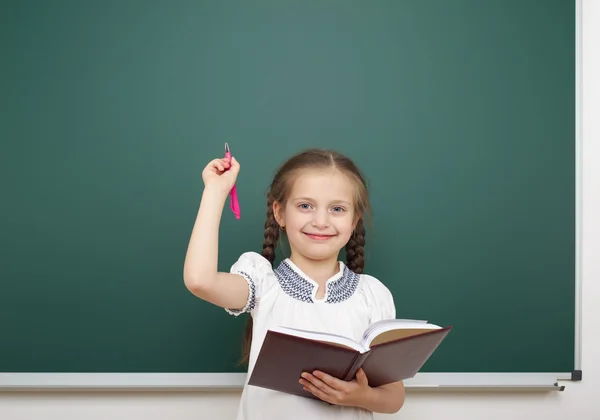 Schoolmeisje met boek in de buurt van schoolbestuur — Stockfoto