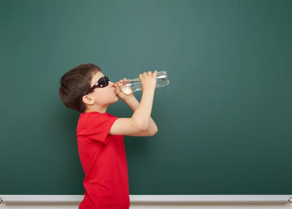 Menino com garrafa de água e placa da escola — Fotografia de Stock