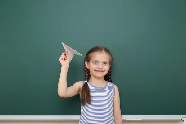 Schoolgirl with paper plane near school board — Stock Photo, Image