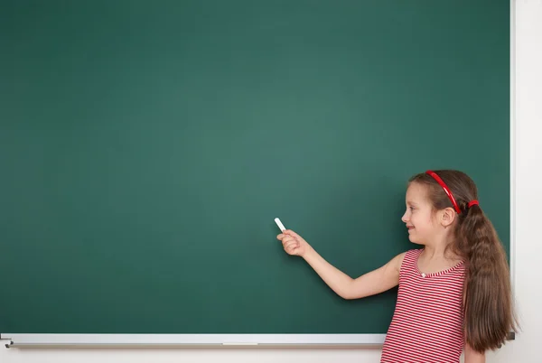 Schoolmeisje schrijven op school board — Stockfoto