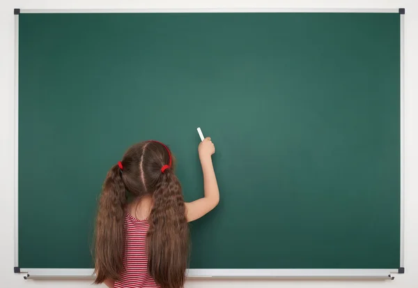 Schoolmeisje schrijven op school board — Stockfoto