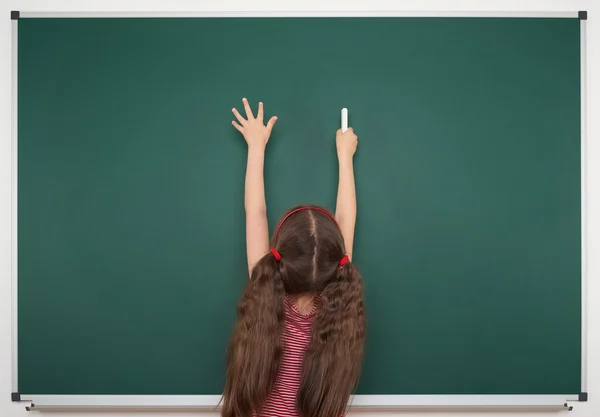 Schoolmeisje schrijven op school board — Stockfoto