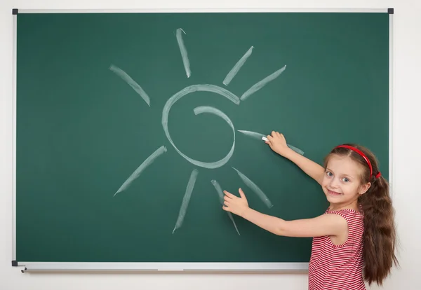 Mädchen zeichnet Sonne auf Schultafel — Stockfoto