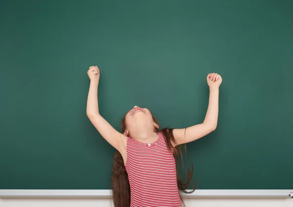 Schoolmeisje schrijven op school board — Stockfoto