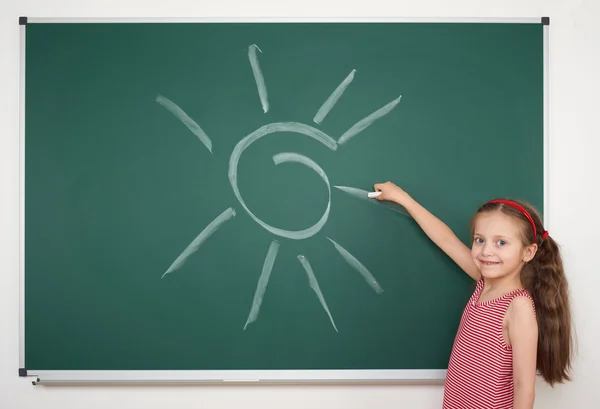 Mädchen zeichnet Sonne auf Schultafel — Stockfoto