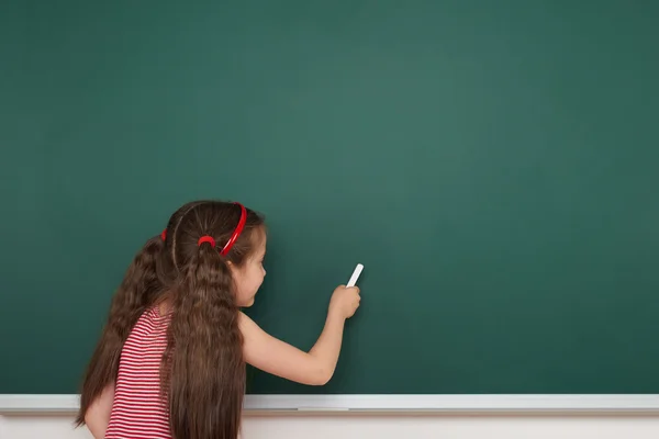 Écolière écrire sur le conseil scolaire — Photo