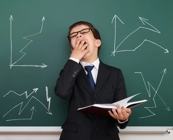 Sleepy boy in suit on school board background with graph — Stock Photo, Image