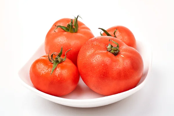 Los tomates en el plato sobre blanco —  Fotos de Stock