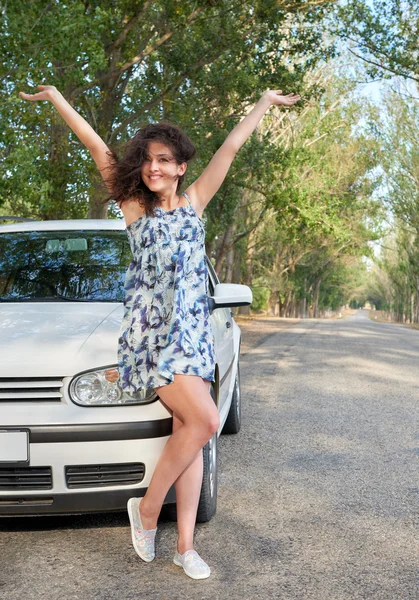 Chica en la carretera brazos abiertos cerca de coche blanco — Foto de Stock