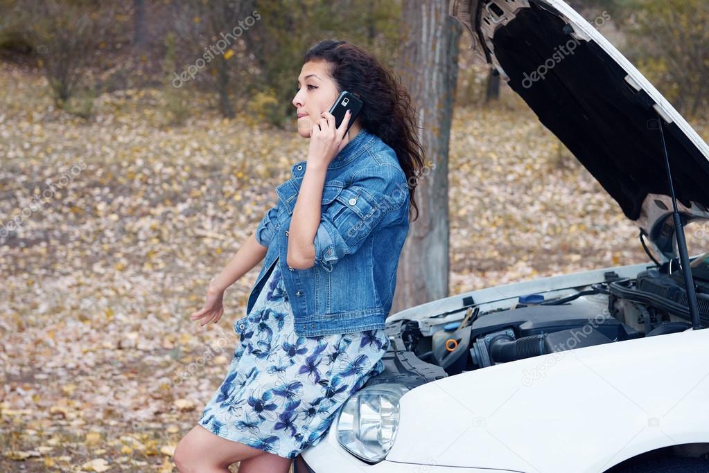 Woman with broken car talk on phone