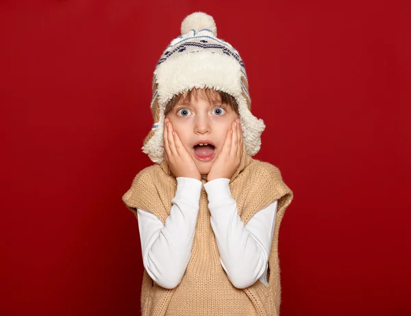 Winter holiday concept - girl in hat and sweater on red background — 스톡 사진