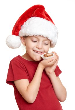 Noel Baba şapkalı kız kurabiye yemek ve kendini - kış tatil Noel kavramı yalamak