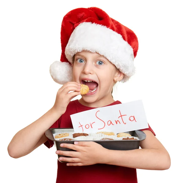 Κορίτσι με το καπέλο santa τρώνε μπισκότα - χειμερινών διακοπών Χριστουγέννων έννοια — Φωτογραφία Αρχείου
