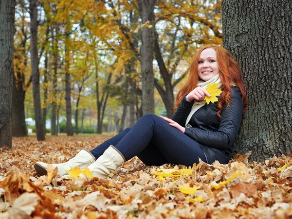 Rödhårig tjej med blad i stadsparken, höstsäsong — Stockfoto